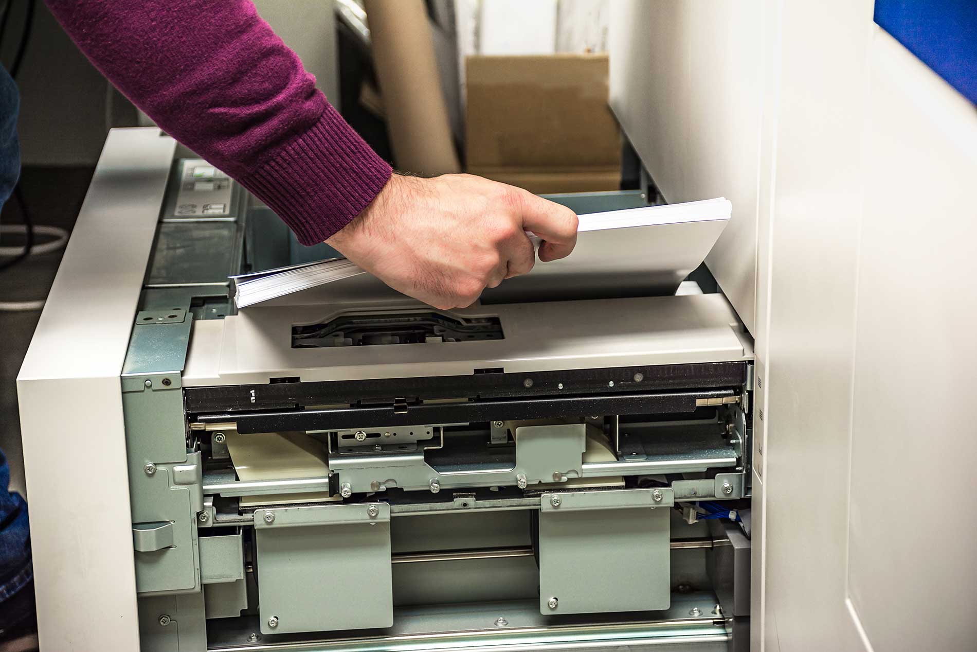man putting paper into a printer